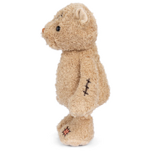 Load image into Gallery viewer, Side profile of a light brown teddy bear with a stitch on its arm and a red and white checkered patch on foot , on a white background.