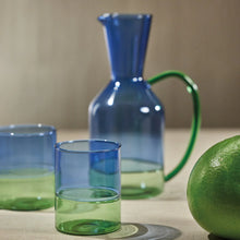 Load image into Gallery viewer, A set of two-toned glassware with blue and green colors, including a tall pitcher, and two  highball glasses and a lime, with a beige background.