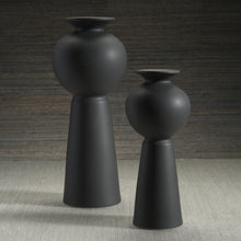 Load image into Gallery viewer, Two matte black modern vases with sculptural silhouettes, placed against a gray wooden background and surface.