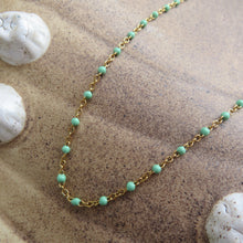 Load image into Gallery viewer, Gold chain necklace with aqua colored beads on a sandy background