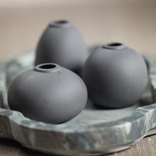 Load image into Gallery viewer, Three matte charcoal finished clay bud vases in assorted shapes placed on a marble surface tray , beige background.