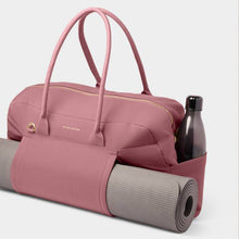 Load image into Gallery viewer, A two handled mauve colored gym bag with a gray yoga mat in mat holder, and a gray clear water bottle in side pocket. Gym bag has a gold zipper and accents. White background.