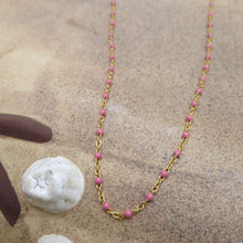 Load image into Gallery viewer, Necklace with pink beads and gold chain on a sandy surface