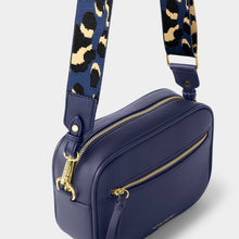 Load image into Gallery viewer, A navy-colored crossbody bag featuring  gold-tone hardware, and a blue leopard print strap, on a white background.