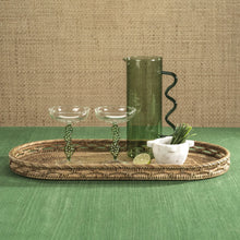 Load image into Gallery viewer, Decorative setting with wicker tray, green  stemmed martini glasses, and a green glass pitcher on green surface and textured brown background.