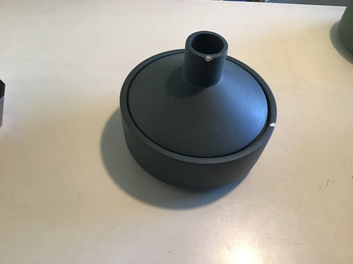 A black candle dish with a chipped lid on a white surface.