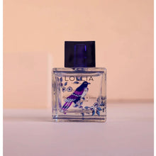 Load image into Gallery viewer, A bottle of &quot;LOLLITA&quot; travel sized perfume with a floral design and a blue bird on the label. The bottle has a clear liquid visible inside and a dark cap. On a pink surface , and against a pink background.