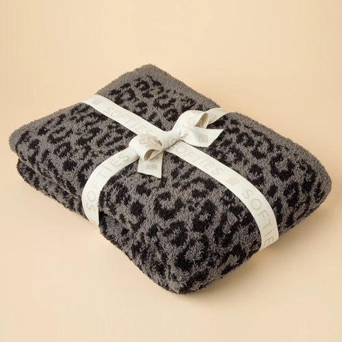 Folded gray and black leopard=patterned blanket tied with a white ribbon printed with 