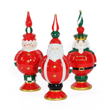 Load image into Gallery viewer, Three hand-painted ceramic holiday cookie jars featuring Santa Claus, Mrs. Claus, and a nutcracker in red outfits with tall red, white, and green finials, displayed against a white background.  