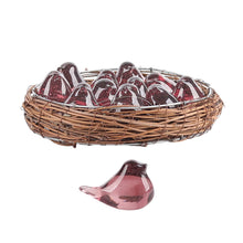 Load image into Gallery viewer, Mini translucent pink glass bird figurines arranged in woven twig nest, with a single matching glass bird figurine positioned outside nest on white background.