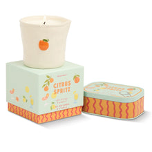 Load image into Gallery viewer, Soy wax ceramic candle in cup container with small orange motif, displayed on the Citrus Spritz product box with matching illustrated candle tin beside it, against a white background.