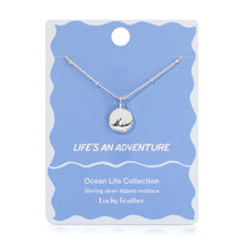 Load image into Gallery viewer, Sterling silver-dipped necklace featuring a small wave charm pendant and a chain with delicate beaded accents, displayed on a blue &quot;Life&#39;s An Adventure&quot; Ocean Life Collection card by Lucky Feather with a white wavy border against a white background.  