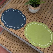 Load image into Gallery viewer, Two round placemats, one blue and one green, on a wooden surface with a plant in the background.