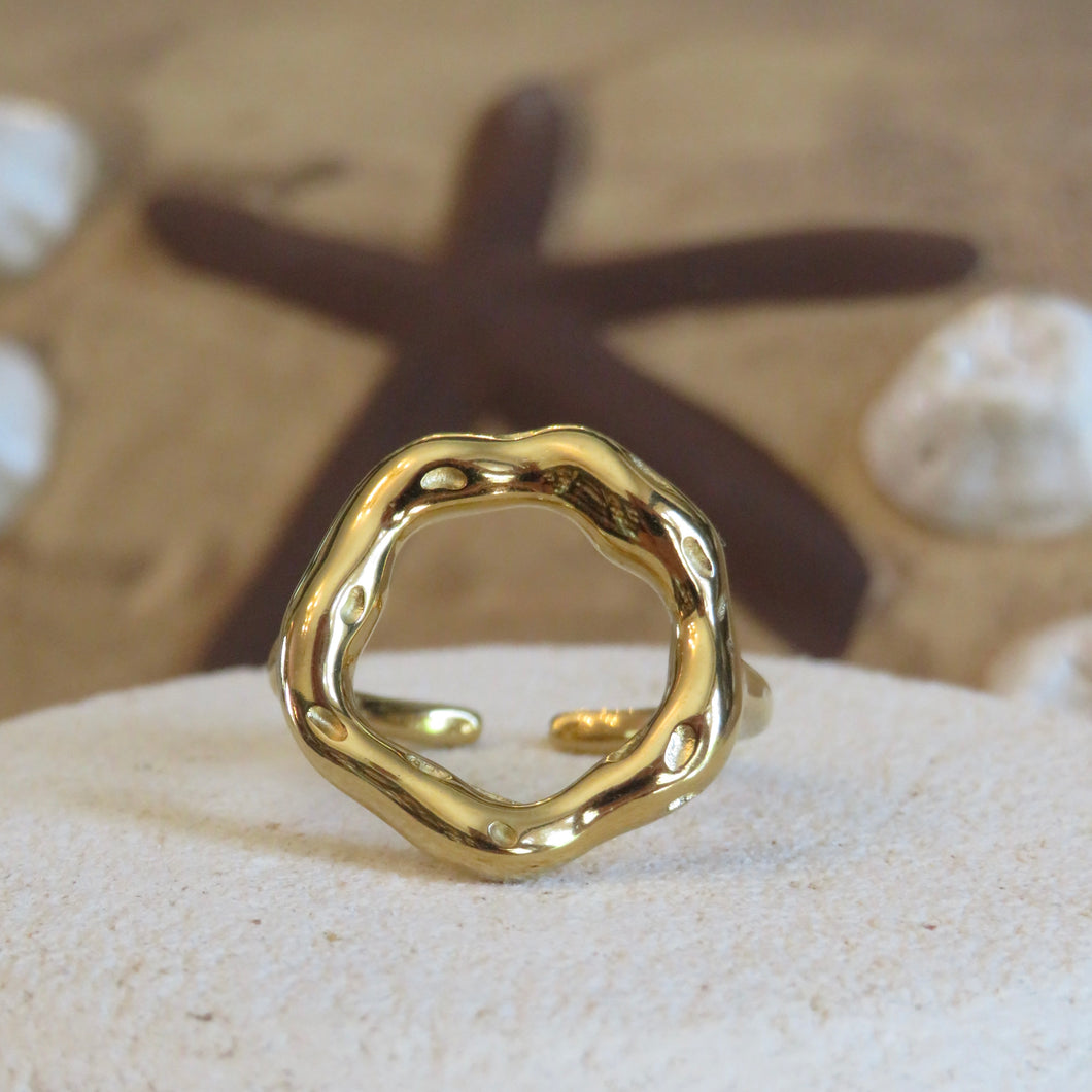 Gold ring on a textured surface with a starfish in the background