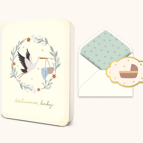 A slightly opened white greeting card with stork and baby bassinet illustration, accompanied by a matching envelope and sticker seal.
Card has 