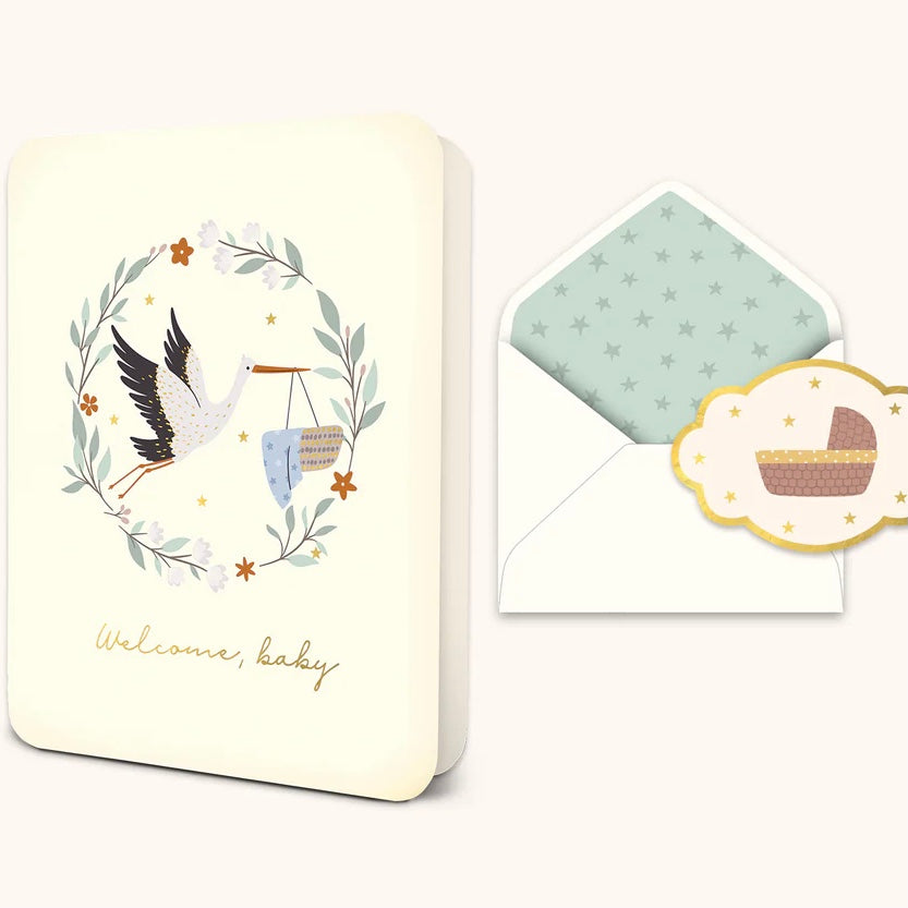 A slightly opened white greeting card with stork and baby bassinet illustration, accompanied by a matching envelope and sticker seal.
Card has 