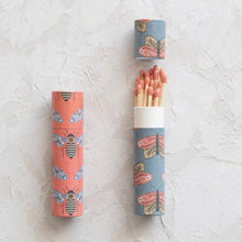 Load image into Gallery viewer, Two tube boxes of matches with an insect pattern. One tube is pink with a bee design. The second tube is blue with a butterfly pattern and is open revealing the long red tipped matches. Both are against a white textured  background. 