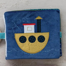 Load image into Gallery viewer, Fabric book with a boat design on a textured surface