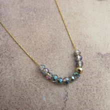 Load image into Gallery viewer, Necklace with iridescent beads and gold chain on a textured surface
