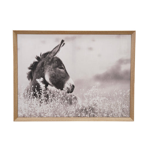 Framed artwork of a donkey in a field with a wooden frame, hanging on white wall.
