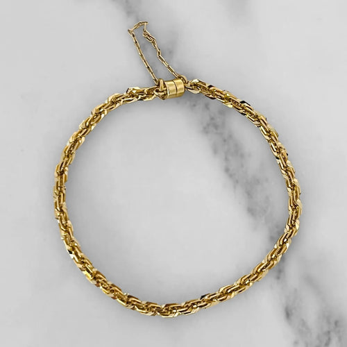 Gold rope bracelet with a magnetic clasp. White marble background. 