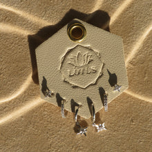 Load image into Gallery viewer, Silver-plated earring set with star studs, pave huggies, and dangling star charms, displayed on a cream LOTUS card against  textured tan surface. 