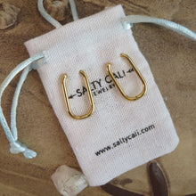 Load image into Gallery viewer, Gold hoop earring set and white jewelry bag with &quot;SALTY CALI JEWELRY , www.saltycali.com&quot; against a beach background.