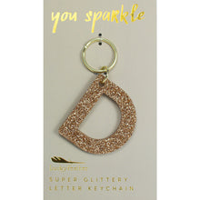 Load image into Gallery viewer, Gold glittery letter &quot;D&quot; keychain on a gray card with &quot;you sparkle&quot; in gold text, displayed on a white background. 