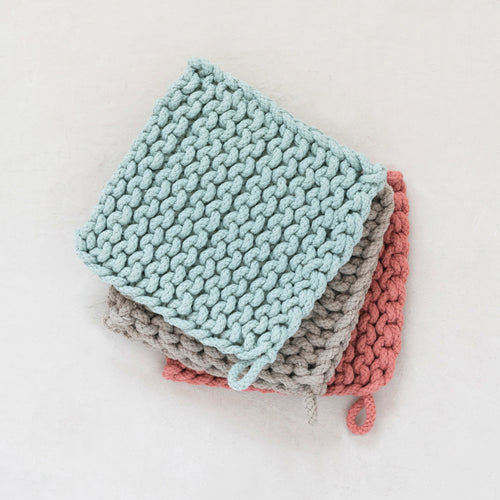 Stack of three square cotton crochet pot holders with a hanging loop in blue, gray, and pink colors, against a white background. 