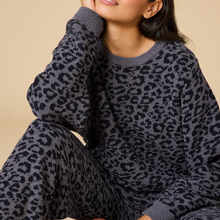 Load image into Gallery viewer, Person in a seated pose wearing a soft gray lounge set with a black leopard print pattern, shown against a soft beige background. 