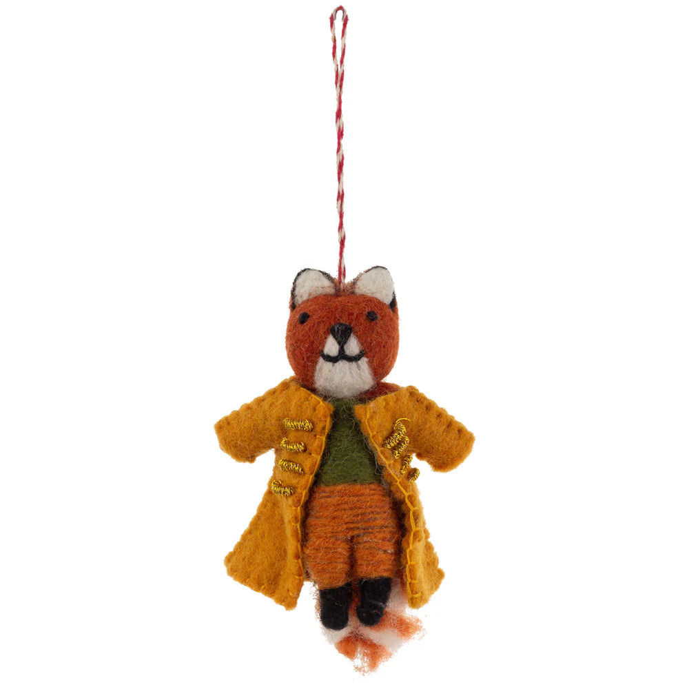 Red fox felt ornament wearing a mustard-colored coat with gold stitching, green shirt, and tan pants. The fox has a white-tipped tail, black shoes, and a red-and-white hanging loop, displayed against a white background.  