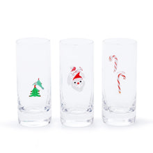 Load image into Gallery viewer, ZODAX Holiday Shot Glasses, front view of three tall clear shot glasses with thick bases, featuring raised motifs of a green Christmas tree with red accents, a red-and-white Santa face, and red-and-white striped candy canes against a white background.