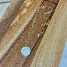 Load image into Gallery viewer, Gold chained necklace with a round mother of pearl pendant on a wooden surface.