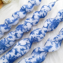 Load image into Gallery viewer, Blue-and-white floral twisted taper candles made of paraffin, arranged on a white textured surface. 