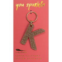Load image into Gallery viewer, Gold glittery letter &quot;K&quot; keychain on a pink card with &quot;you sparkle&quot; in gold text, displayed on a white background.