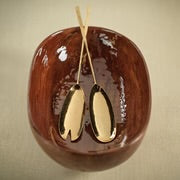 Load image into Gallery viewer, Polished gold serving set with two long-handled oval spoons resting inside a glossy wooden-looking bowl, displayed on a light beige surface. 