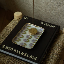 Load image into Gallery viewer, Rectangular enameled tray with a red, gray, and green floral pattern and painted gold edging, holding an incense stick on a book.
