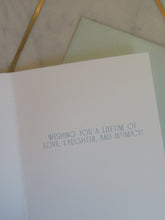 Load image into Gallery viewer, Greeting card with &quot;WISHING YOU A LIFETIME OF LOVE,LAUGHTER, AND INTIMACY&quot; text and a light blue envelope on a marble surface.