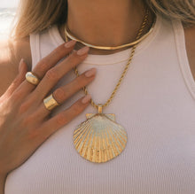 Load image into Gallery viewer, Person wearing a 14K gold double semi-matte plated brass choker necklace layered with a gold shell pendant necklace and chunky gold rings, shown against  a white ribbed tank top. 