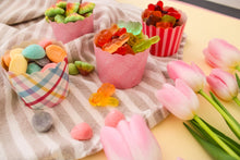 Load image into Gallery viewer, Assorted gummy candies in decorative paper cups on a striped cloth with pink tulips.