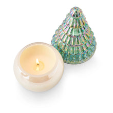 Load image into Gallery viewer, Fresh Balsam Pearl Tree Candle, candle with cream wax and a lit wick in a round smooth pearl-finish glass vessel base, with an iridescent green, cone-shaped tree lid featuring ribbed tiers and pink and gold sheen beside it, against a white background. 