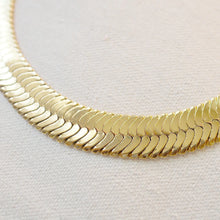 Load image into Gallery viewer, Close-up of the wide gold-plated brass herringbone chain necklace showing the polished links, displayed flat on an off-white textured surface 