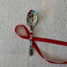 Load image into Gallery viewer, Enameled Holiday Spoons | Four Styles, lifestyle photo of a stainless steel spoon with a mint green enamel background decorated with colorful wrapped gifts in various shaped and sizes with a red ribbon on a cream textured fabric surface. 