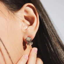 Load image into Gallery viewer, Model wearing gold-plated huggie earrings with clustered pearl accents and sparkling clear crystal detailing, displayed on an ear.