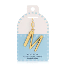Load image into Gallery viewer, 14K gold-plated hand-painted enamel initial bag charm featuring the letter M with a scalloped edge design and a brushed gold finish, attached to a key ring and clasp. Displayed on a white and blue Lucky Feather card with a light blue dotted brush-stroke borders labeled &quot;Bag Charm Hand Painted Enamel.&quot; Displayed on a white background. 