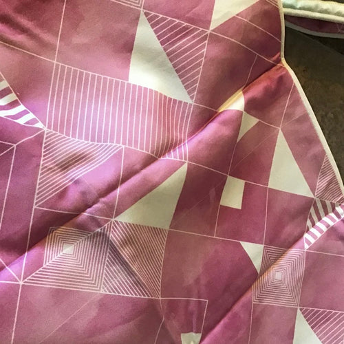 Close-up of a purple fabric with geometric white lines and shapes.