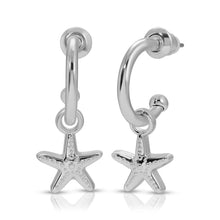 Load image into Gallery viewer, Pair of hoop earrings dipped in sterling silver featuring small dangling starfish charms with textured detailing, displayed against a white background. 