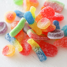 Load image into Gallery viewer, Close-up of assorted sugar-coated gummy candies including sour bottles and rings on a white background. 