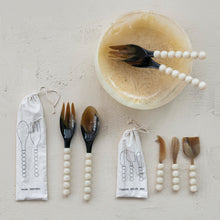 Load image into Gallery viewer, Horn Salad Server Set, displayed with tortoise-toned natural horn spoon and fork heads, white resin bead handles, natural-colored drawstring pouch with illustrated black salad server outline design, coordinating Horn Cheese Knives Set, and serving bowl on textured neutral surface. 