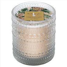 Load image into Gallery viewer, Balsam &amp; Fir, angled view of a cream soy candle in a clear glass jar with raised dot texture and an unlit single wick, topped with decorative paper featuring green evergreen branches, brown pinecones, and a gold-colored panel with the scent name and product type in dark lettering against a white background.